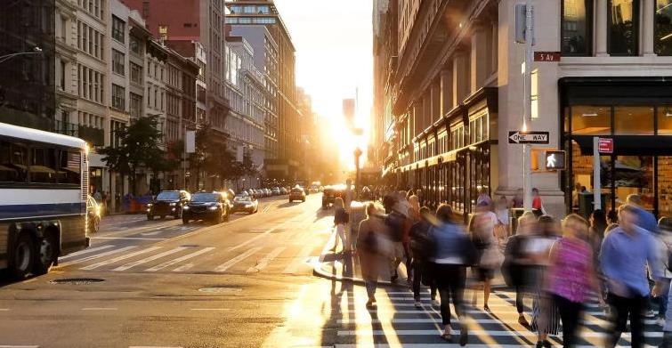 Crowd of anonymous people in motion walking across the busy intersection of Fifth Avenue and 23rd Street in New York City