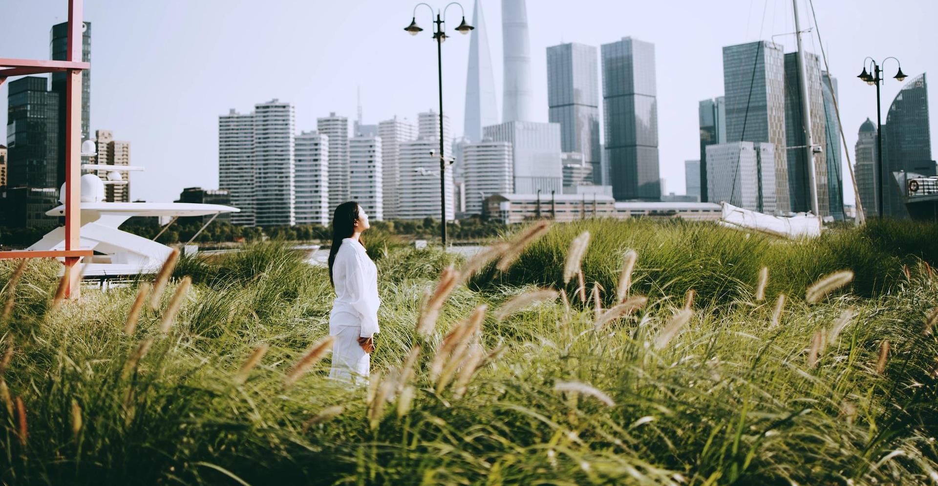 Young Asian woman standing in the park looking at skyscrapers in downtown Shanghai