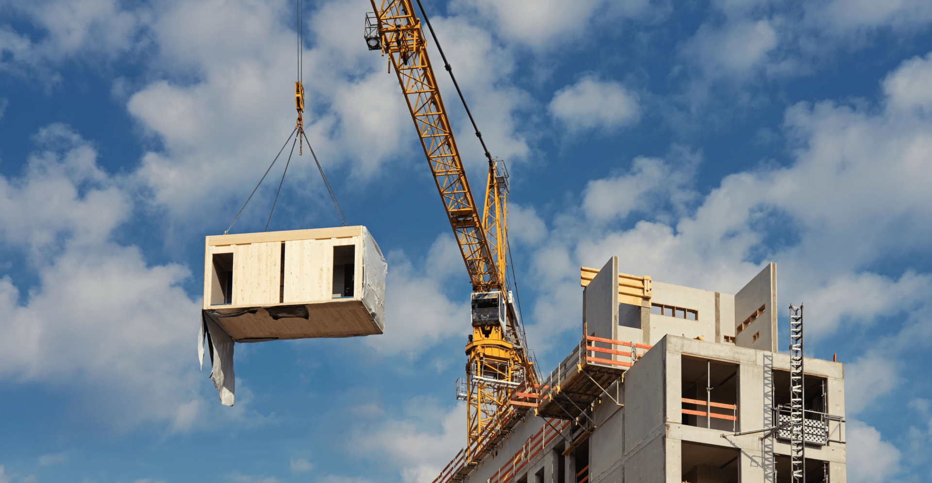 Construction crane hoisting a building in progress at a construction site