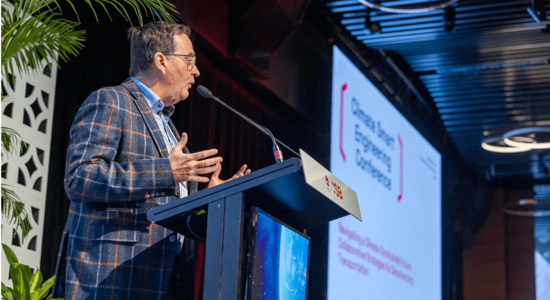 A suited man addresses the audience at a conference, sharing insights and information during his speech.