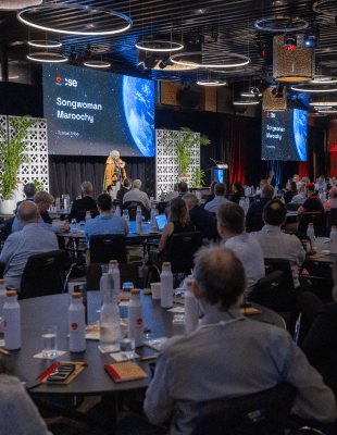 A large crowd of attendees engaged in discussions at a bustling conference venue.