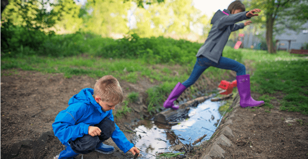 Kinderen spelen in een weiland met regenplassen