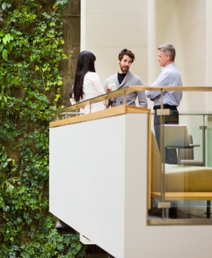 Three individuals engaged in conversation while standing on a balcony, enjoying the view and each other's company.