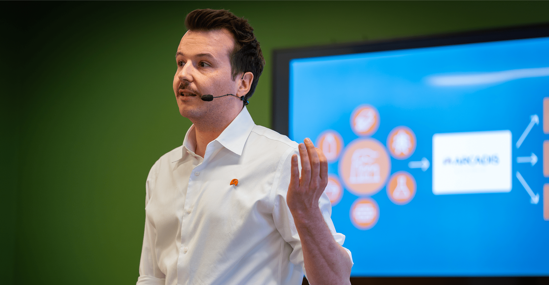 A man presenting in front of a large screen, engaging the audience with visual aids and clear communication.