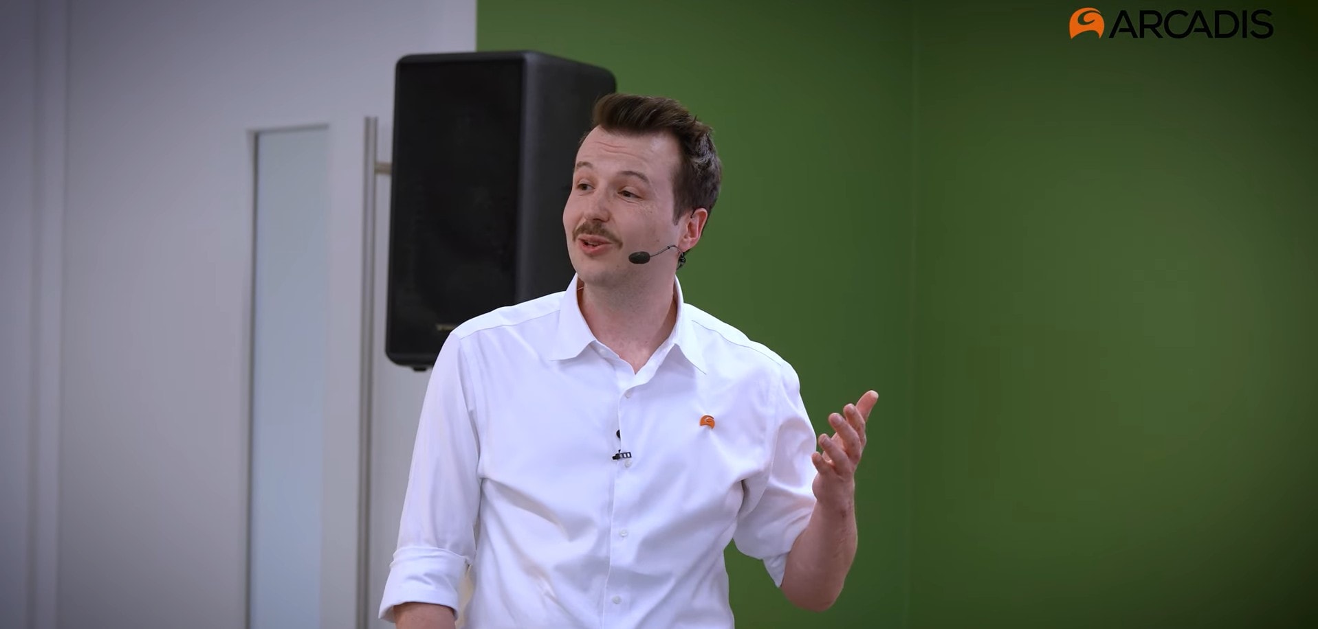 A man presenting in front of a large screen, engaging the audience with visual aids and clear communication.