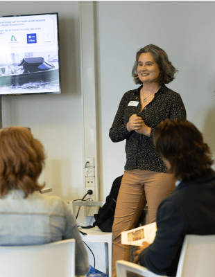 Female speaker delivering a presentation to an audience.