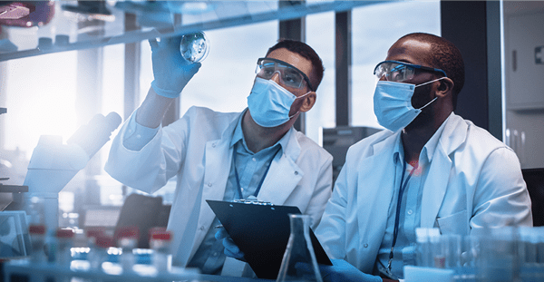 Two researchers in protective gear analyzing a scientific experiment in a laboratory.