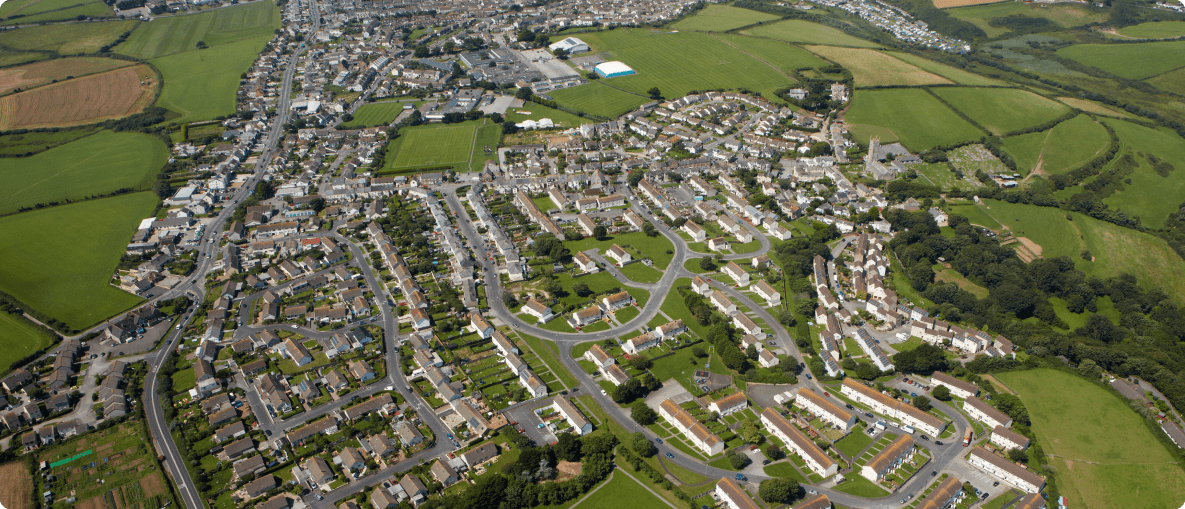 Aerial view of a bustling cityscape, showcasing buildings, streets, and green spaces under a clear blue sky.
