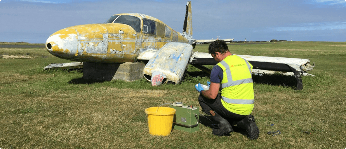 A man in a yellow vest cleans an old airplane, ensuring safety and maintenance in an aviation environment