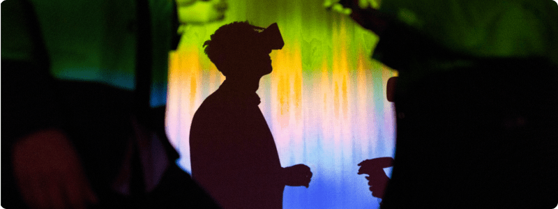 Silhouette of individuals against a vibrant backdrop of colorful lights, creating a striking visual contrast.