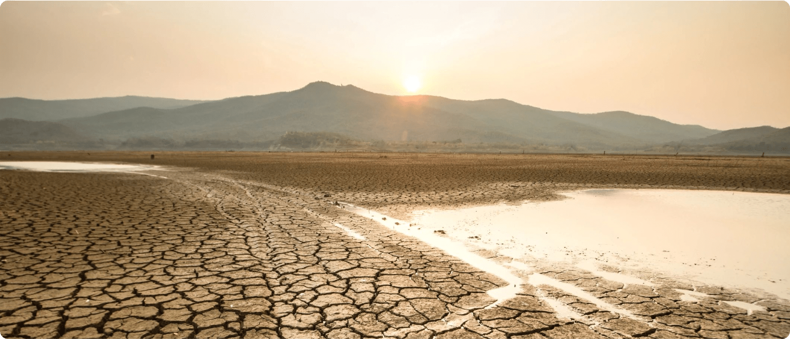 A dry lake bed stretches out under a clear sky, with a mountain rising in the background.