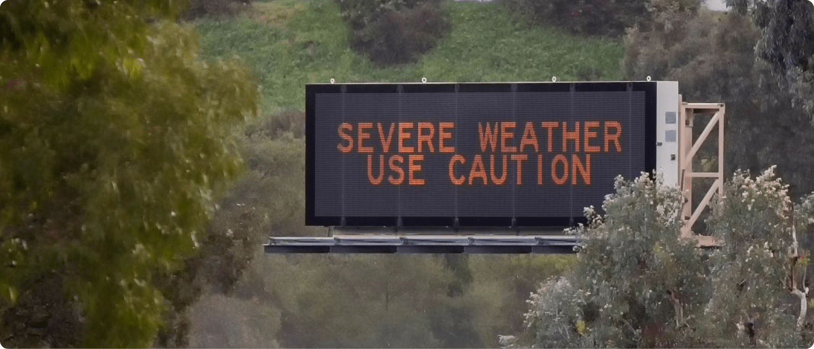 A warning sign advises drivers to exercise caution due to severe weather conditions in the area.