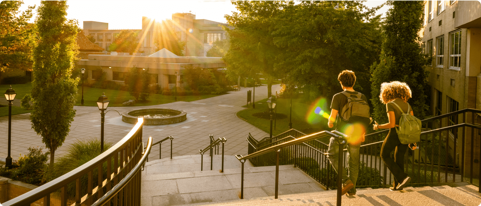 Two people walking down a set of stairs outside a building, capturing a dynamic scene in an urban environment.