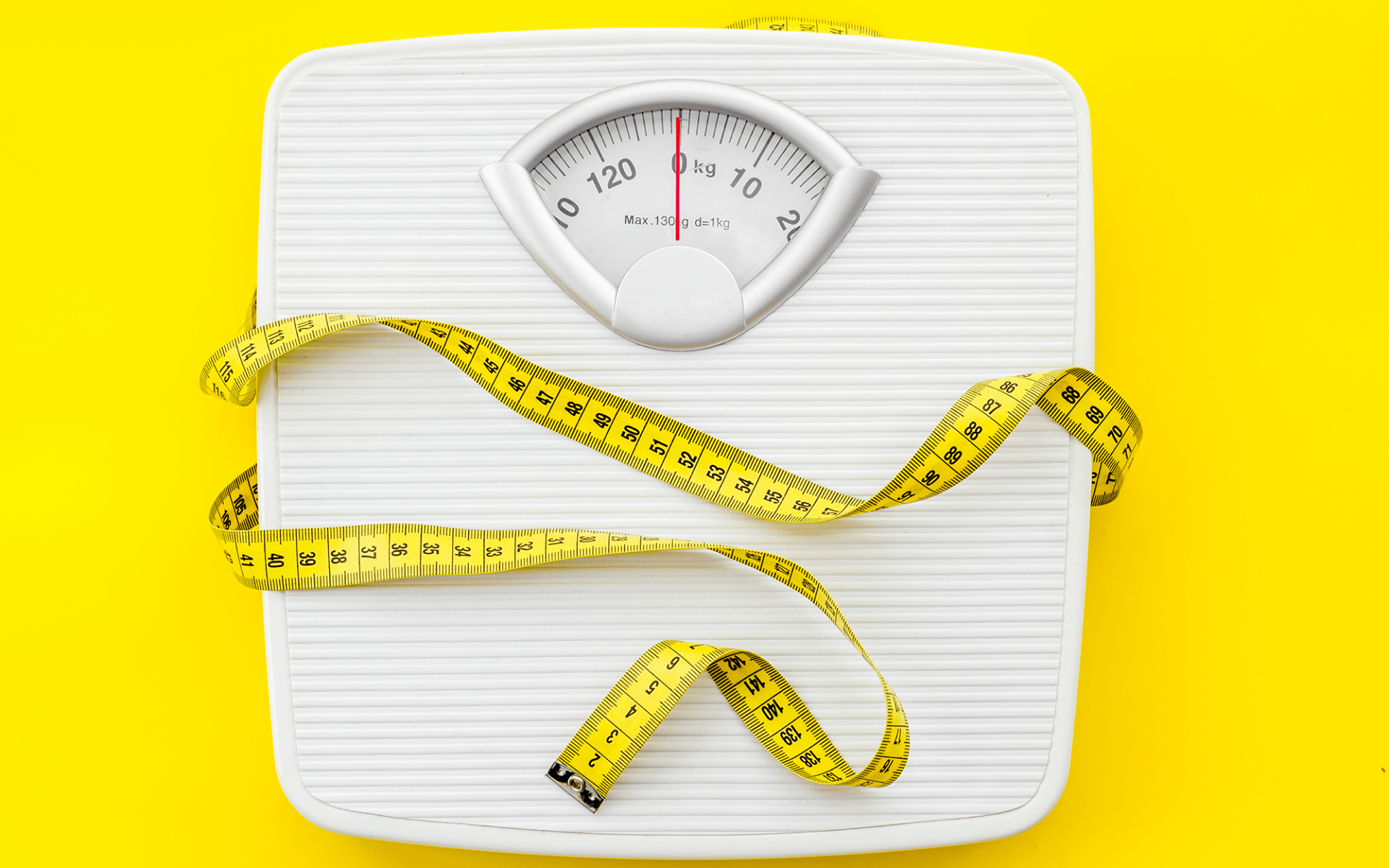 Weight scale and tape measure on yellow background.