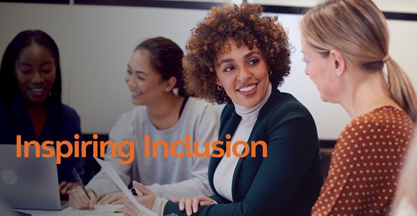 A diverse group of women sitting at a table, with the words "inspiring inclusion" displayed.