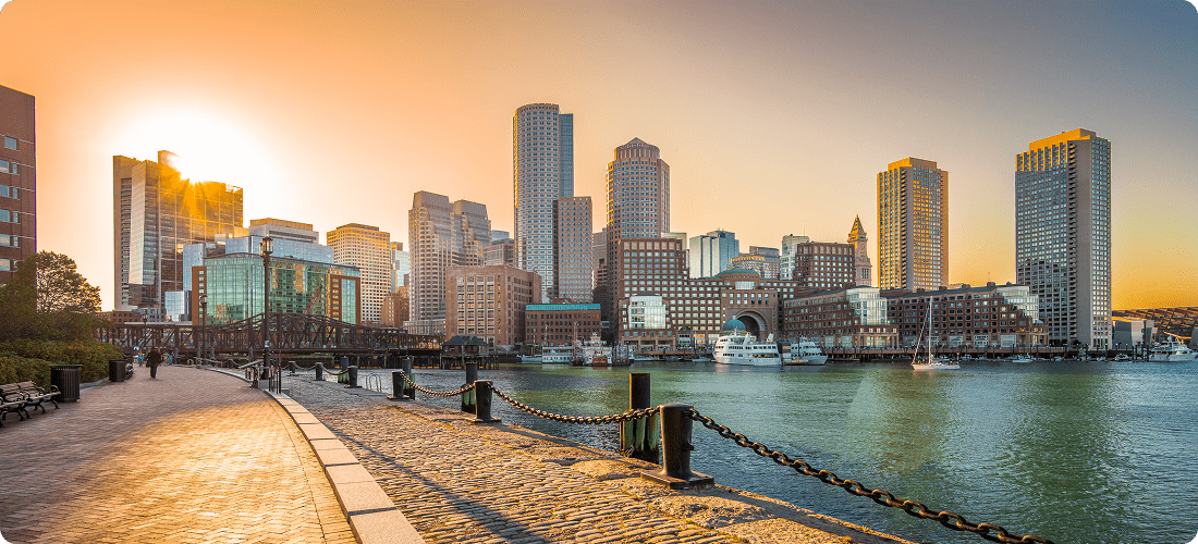 A city skyline featuring tall buildings, a river flowing through, and a dock along the water's edge.