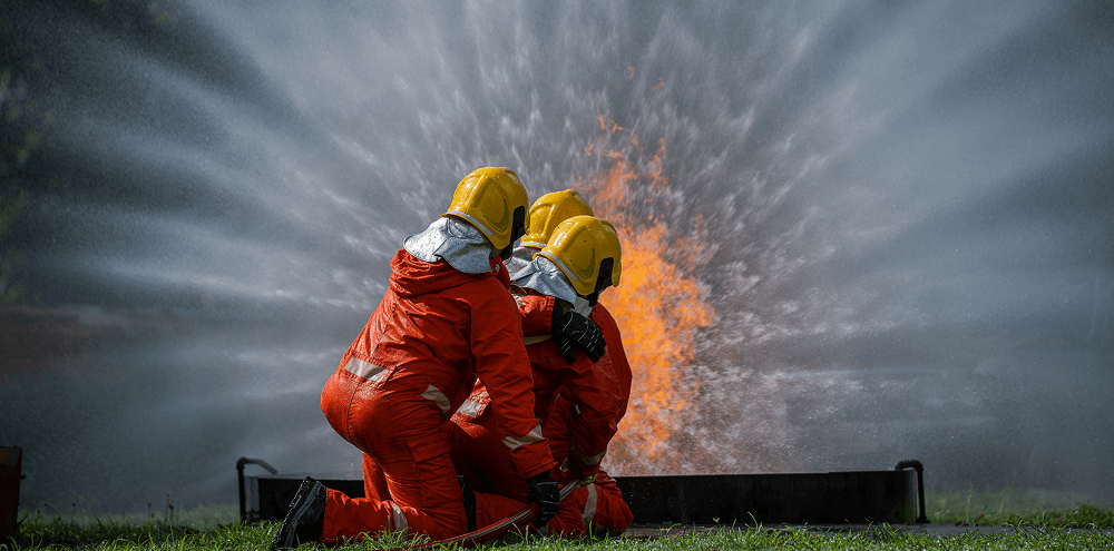 Firefighters in protective gear spray water from a fire hydrant to extinguish a blaze in an urban area.