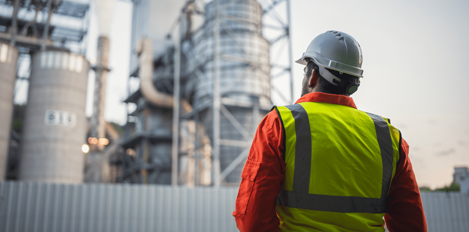 A man with a hard hat and safety vest examines a factory, representing safety protocols in an industrial setting.