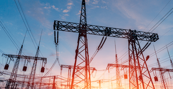 Power lines and towers silhouetted against a colorful sunset sky.