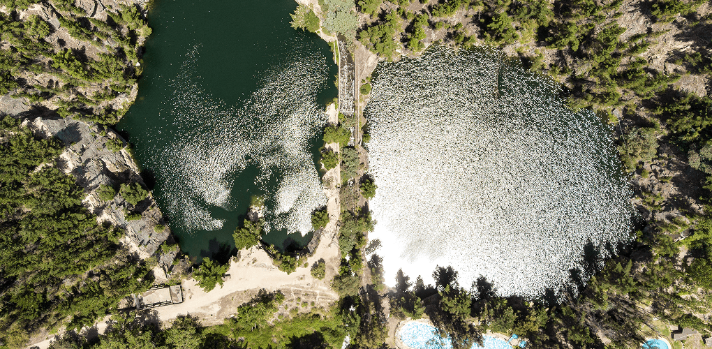 Aerial view showcasing a serene lake surrounded by lush green forest.