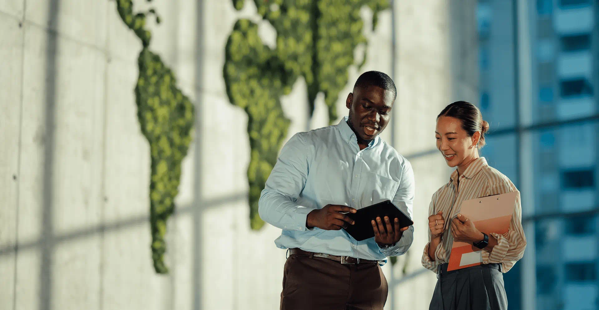  A pair of individuals pose in front of a wall adorned with a globe, suggesting a global theme.