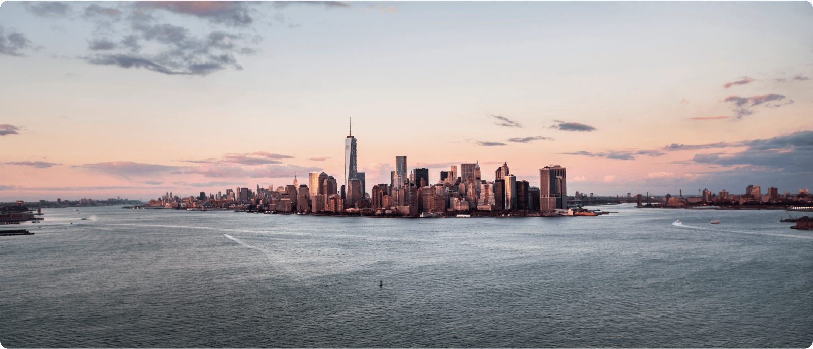 The skyline of a bustling city rises above a tranquil body of water, creating a picturesque urban landscape.