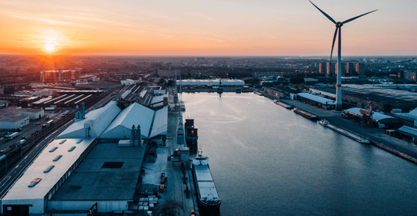 Aerial view of wind turbines silhouetted against a vibrant sunset, showcasing renewable energy in a serene landscape.