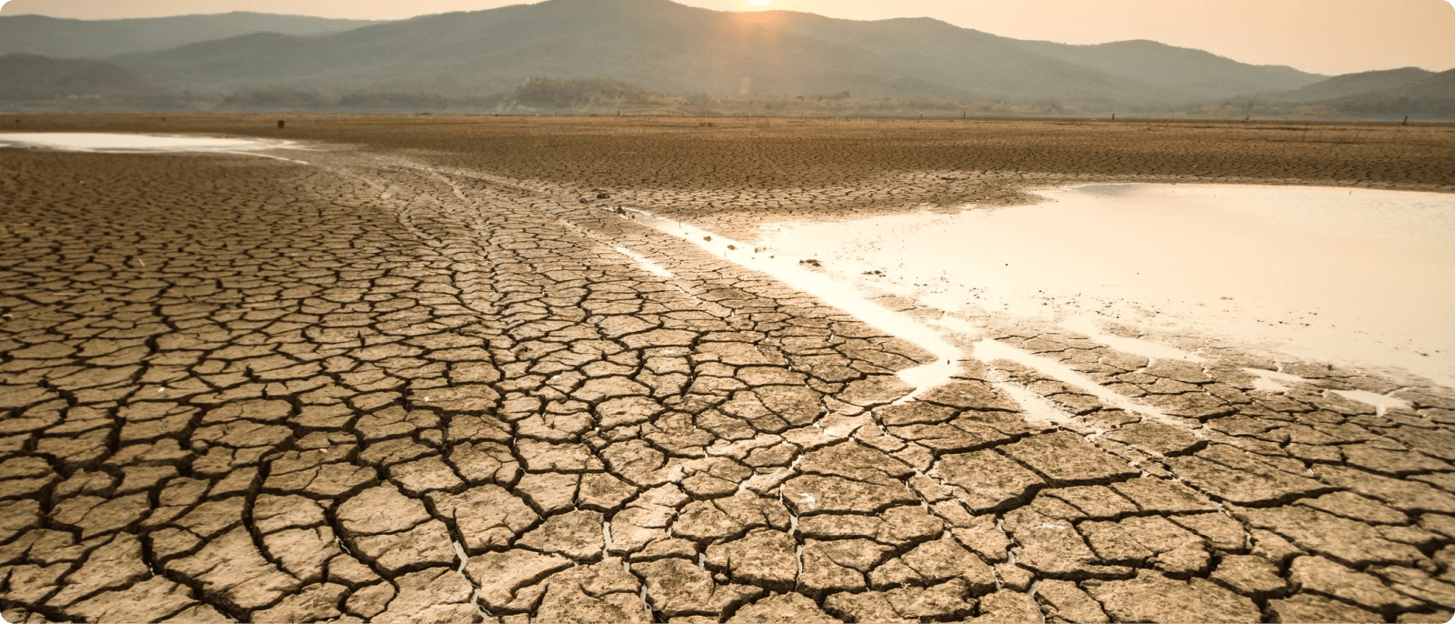 The sun sets over a drought-stricken lake bed.