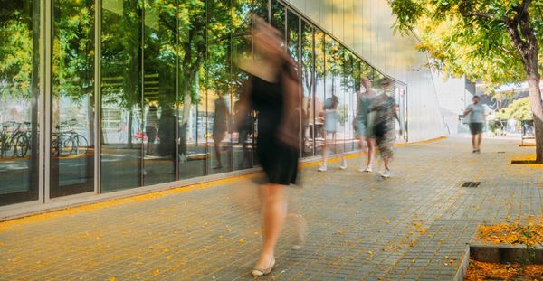 People walking down a sidewalk, captured in a blurry image.