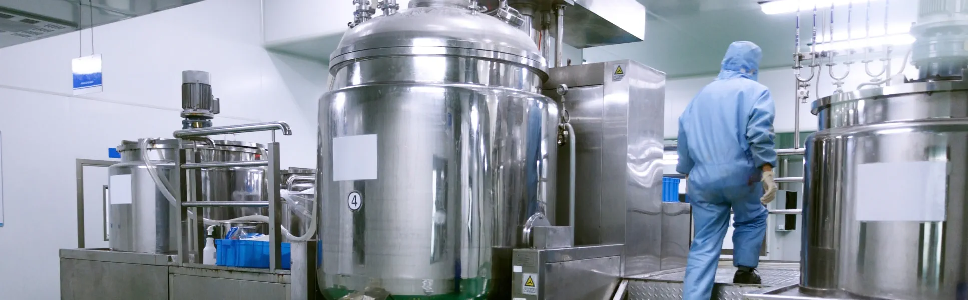 A man in a blue suit stands confidently before a large stainless steel machine, showcasing a professional environment.
