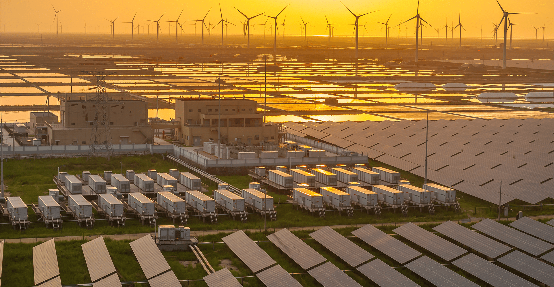 A solar farm and wind turbines at sunset, creating a picturesque scene of sustainable energy against a vibrant sky.
