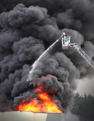 Firefighter ascending ladder to reach burning building.