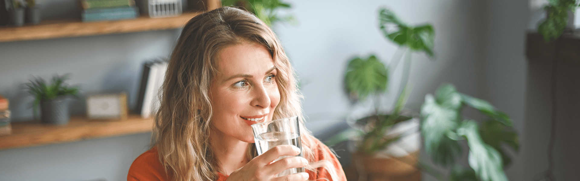 A lady takes a sip of water from a glass.