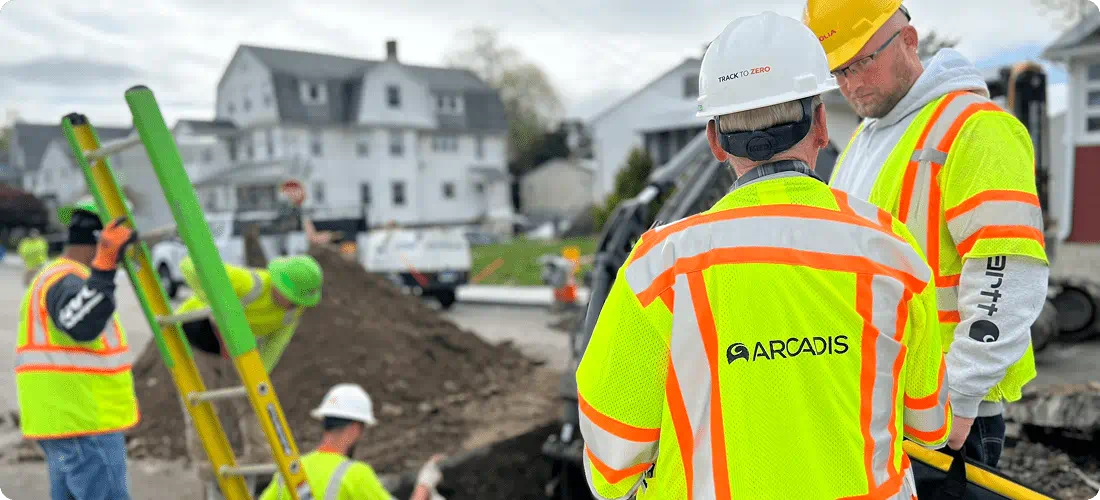 Group of men wearing safety vests and hard hats are working together on a construction site, ensuring safety and progress.