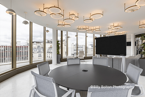 A conference room featuring a large screen at the front and several chairs arranged for attendees.