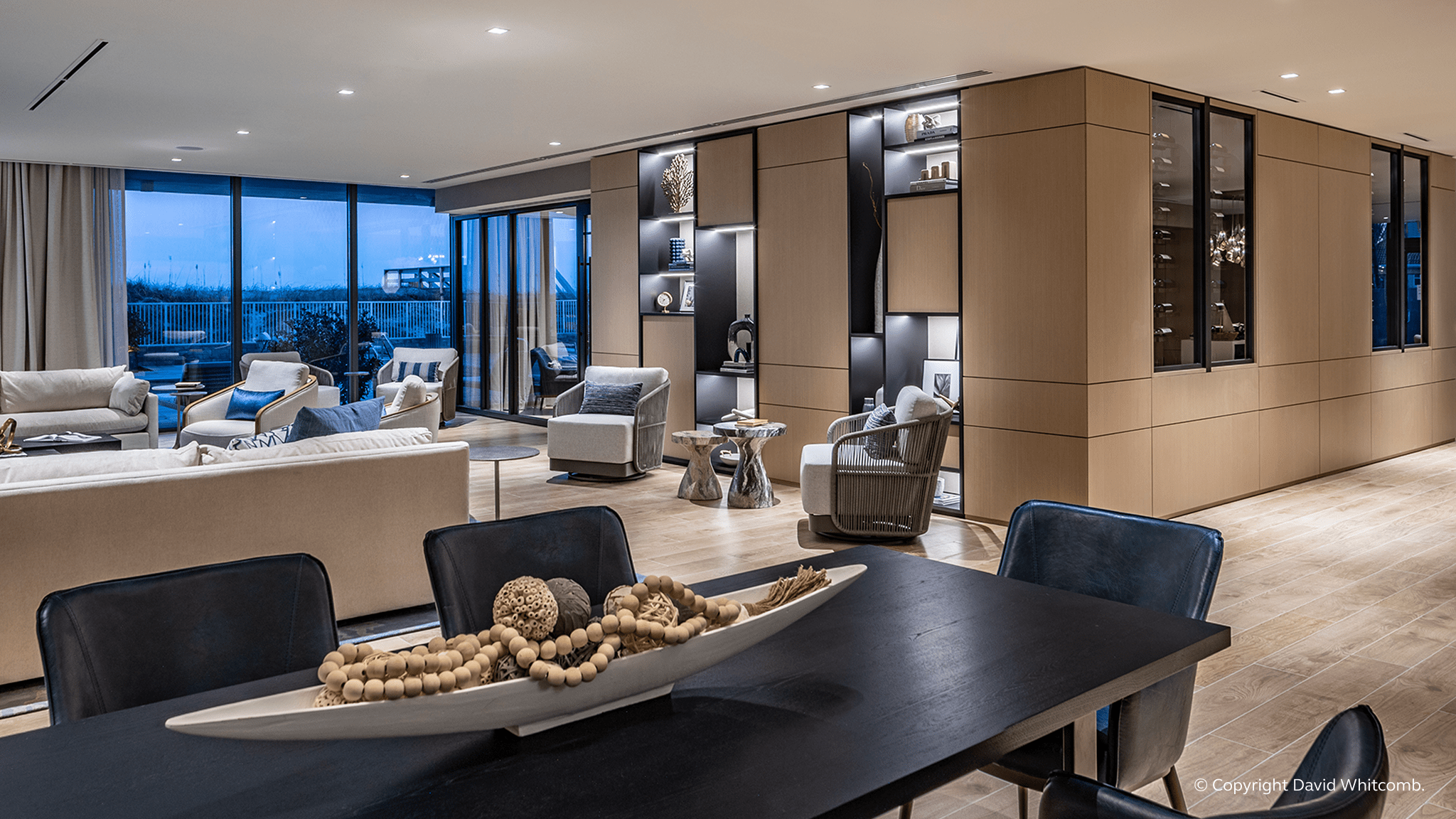 A spacious living room featuring a large window that illuminates a prominent painting on the wall.
