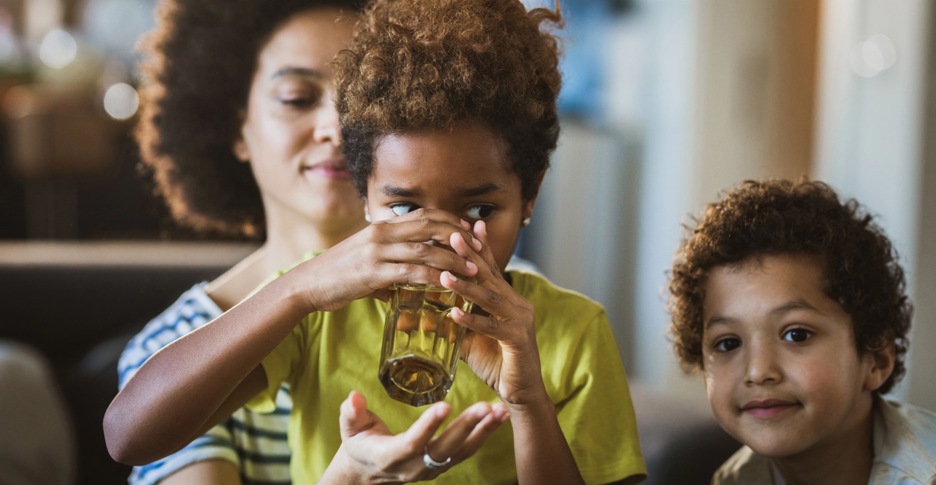 Daughter drinking water with assistance of her mother