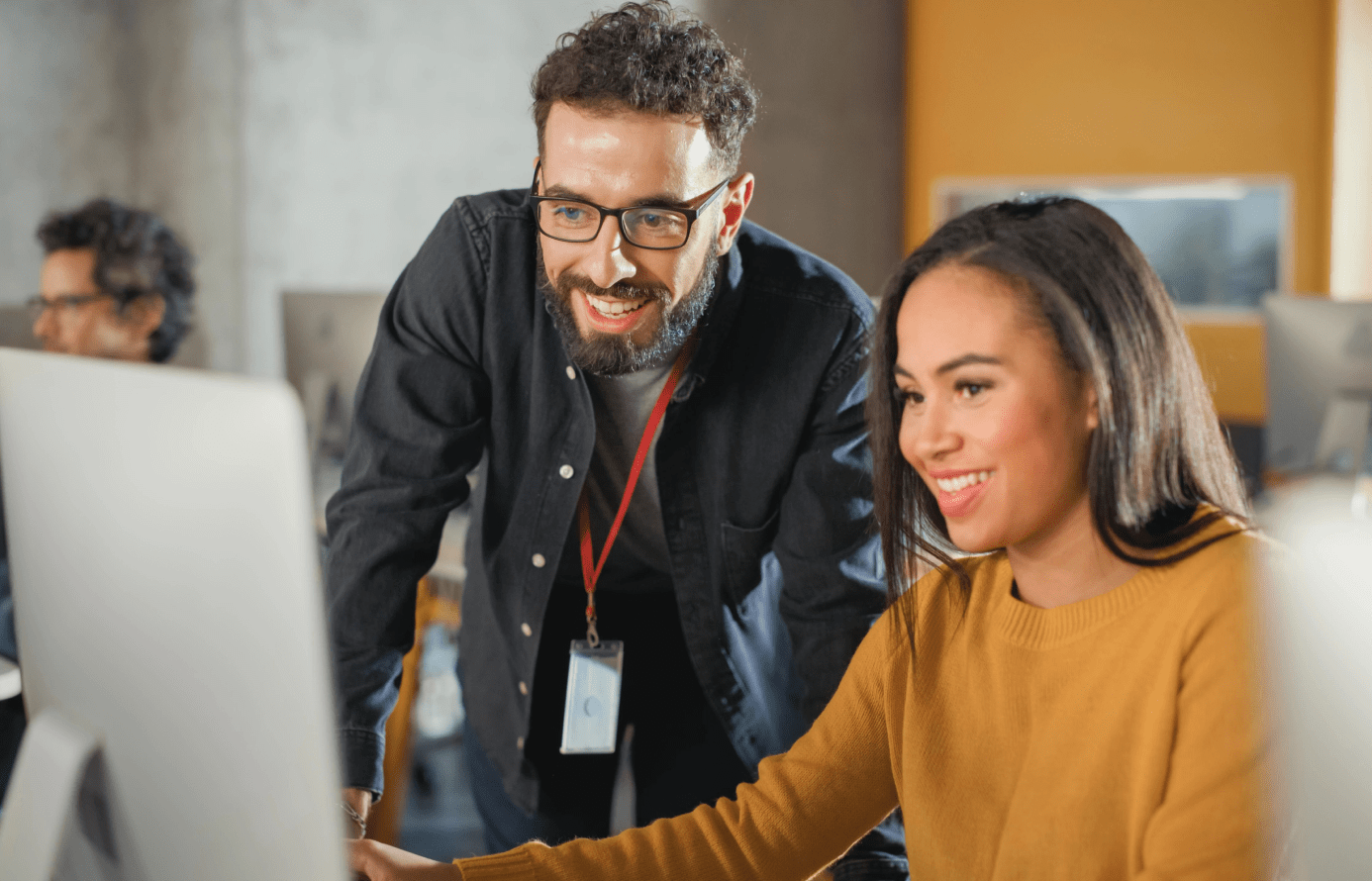 Smiling man and woman engaged in computer work.