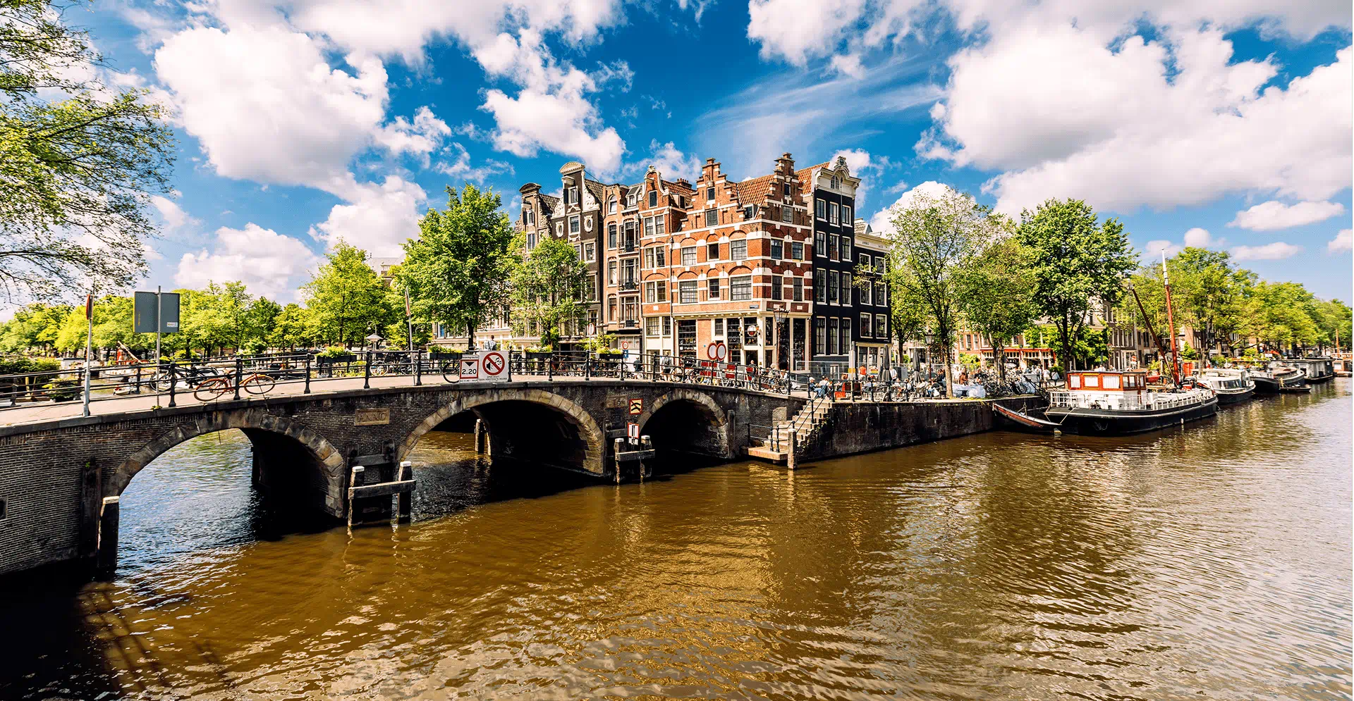 Scenic view of Amsterdam's iconic canals and historic buildings under a clear blue sky.