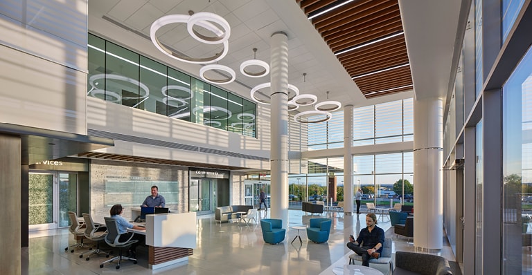 A modern office building lobby featuring individuals seated at desks, showcasing a contemporary workspace environment.
