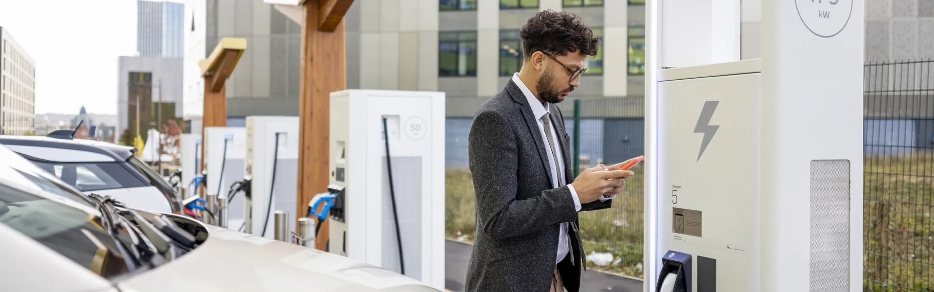 Man using phone to charge electric car.