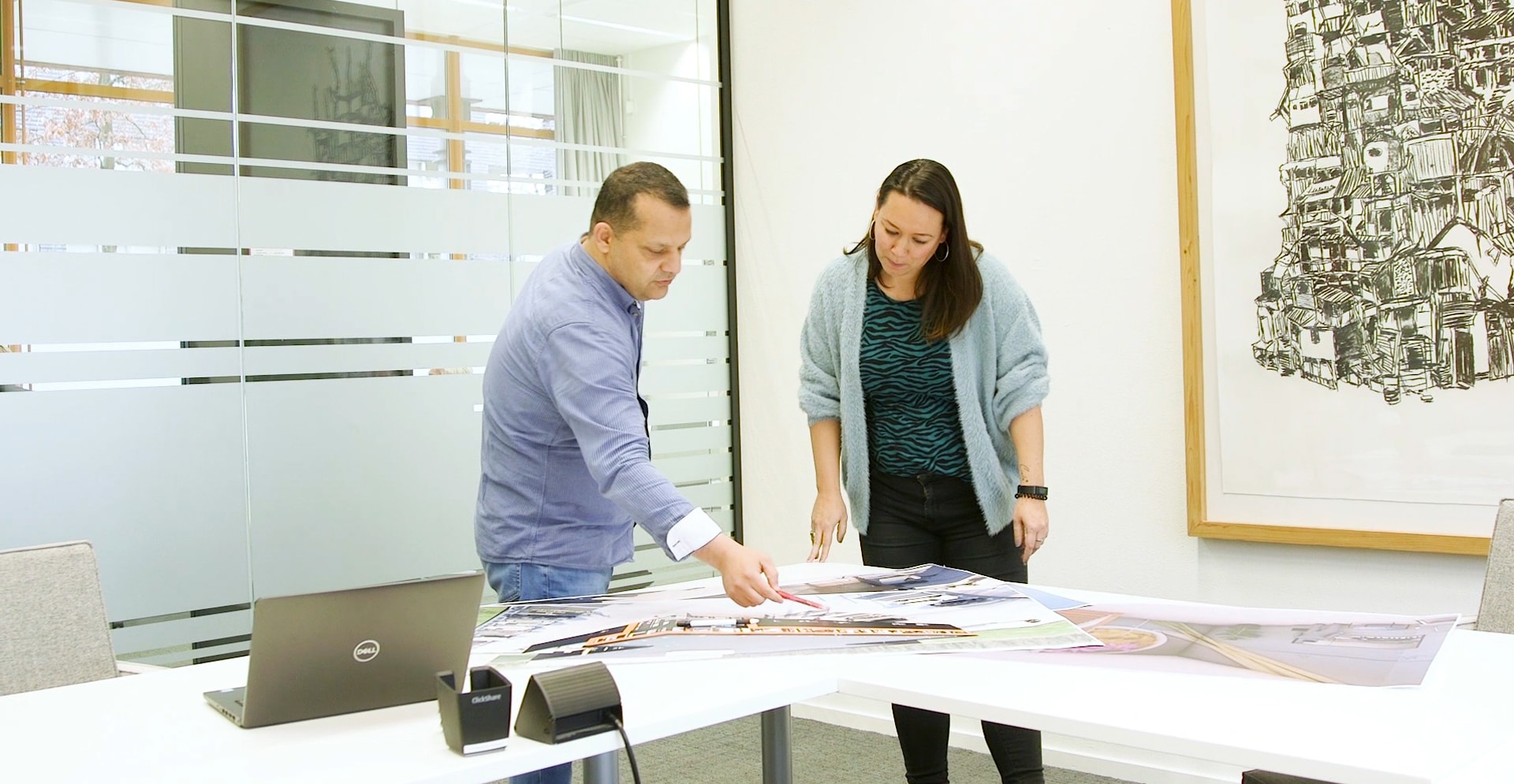 Two individuals collaborating in a office meeting room.
