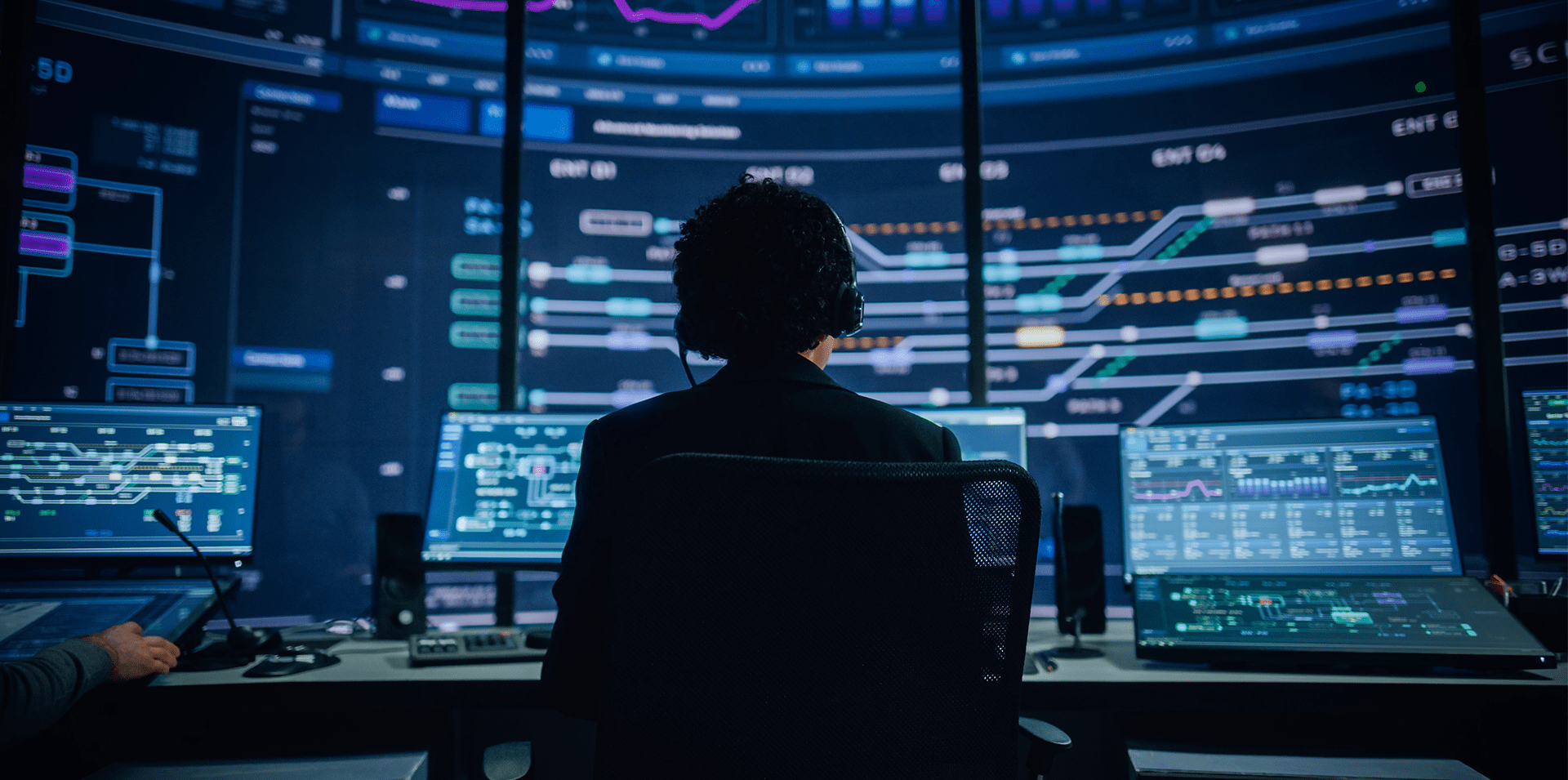 Control room operator monitoring real-time data and digital systems dashboards.