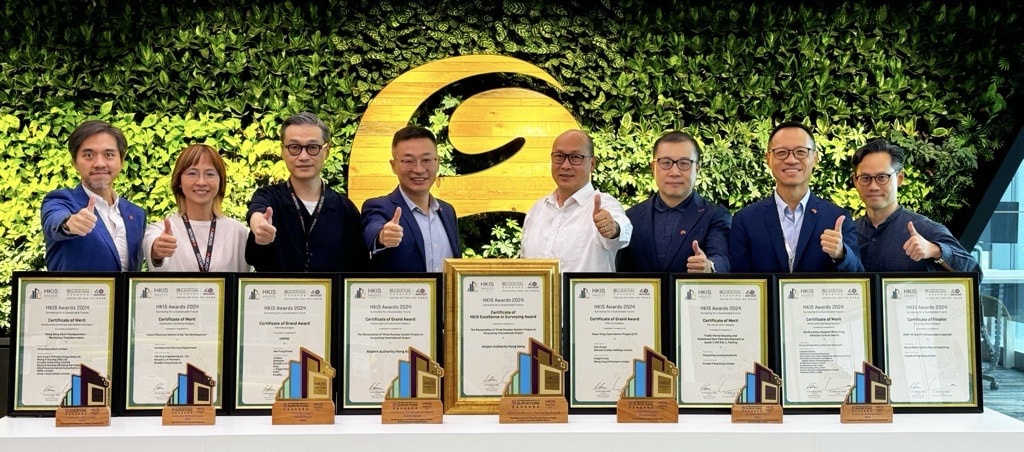A diverse group of individuals displaying their awards while posing for a celebratory photo together.