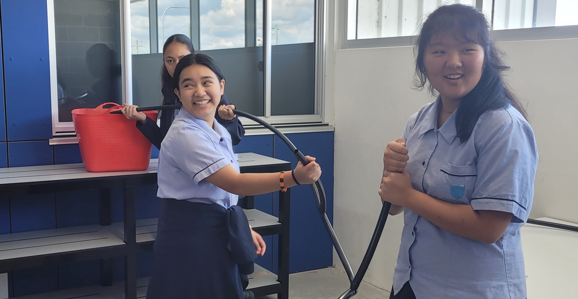 Girls in uniforms holding a hose, possibly engaged in a activity.