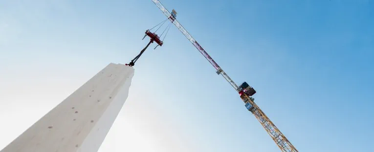 A crane is lifting a wooden post, showcasing the machinery's strength and precision in construction work.