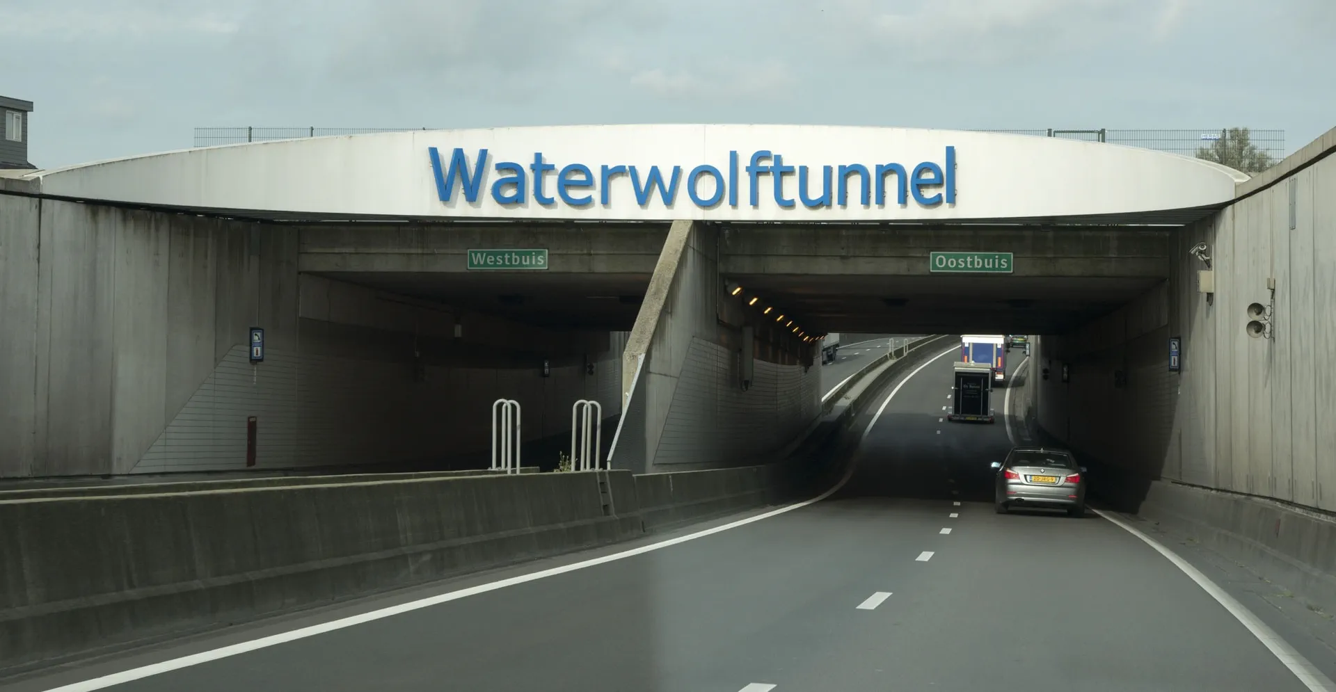 Entrance to the Waterwolftunnel with separate lanes labeled Westbuis and Oostbuis, showing cars entering the tunnel.
