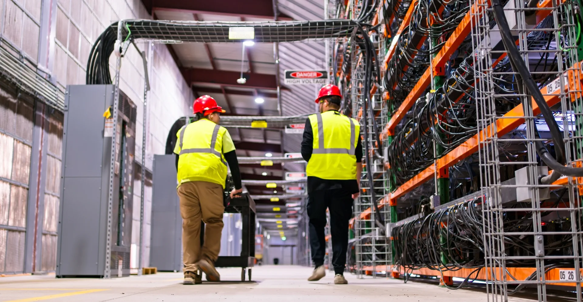 Rear View of Two Technicians Walking Away from the Camera Through Data Center