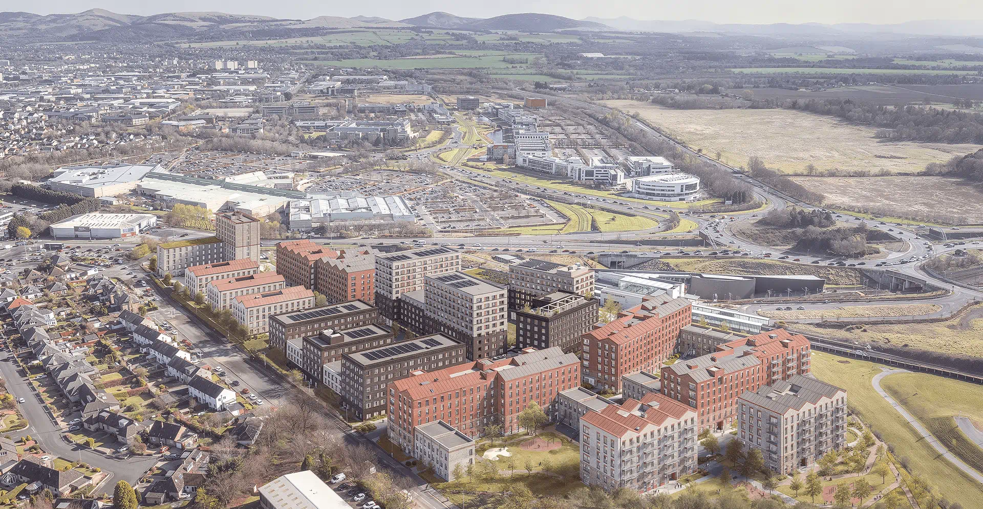Aerial view of a city featuring various buildings and surrounding hills under a clear blue sky.