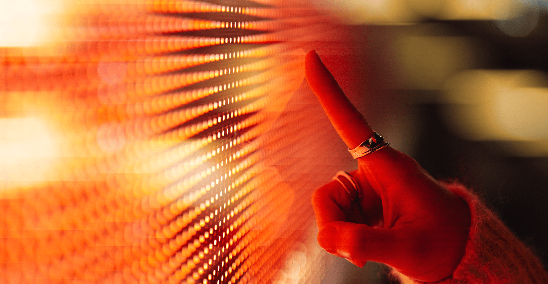 A hand is raised, with a finger pointing at a vivid red screen, suggesting focus on the content displayed.